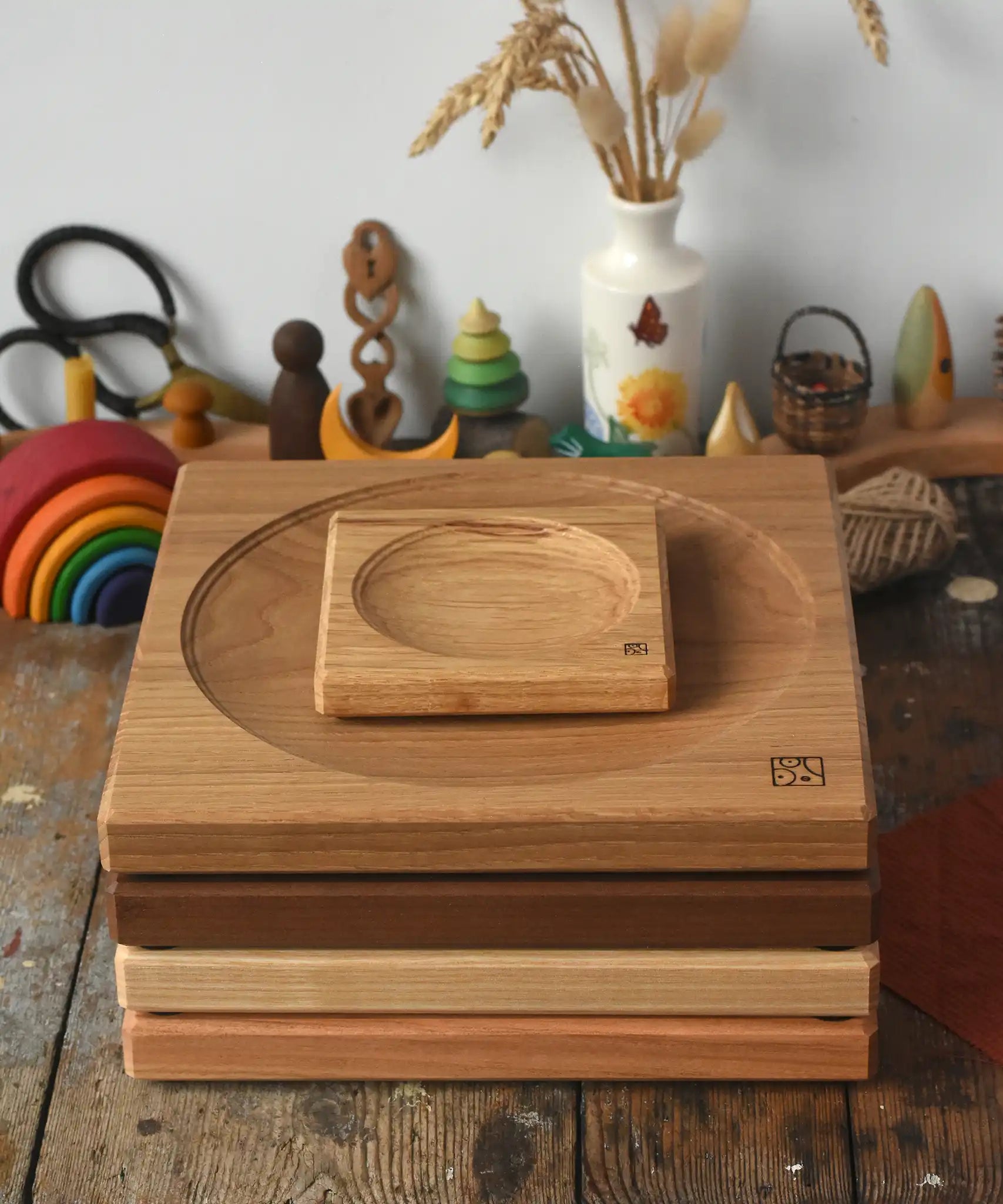 A stack of handmade Mader spinning plates in different woods, cherry, ash, walnut and oak placed on a wooden surface in the Babipur playroom. 