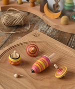 Mader fire spinning top learning set placed on an oak spinning plate on a wooden surface in the Babipur playroom.