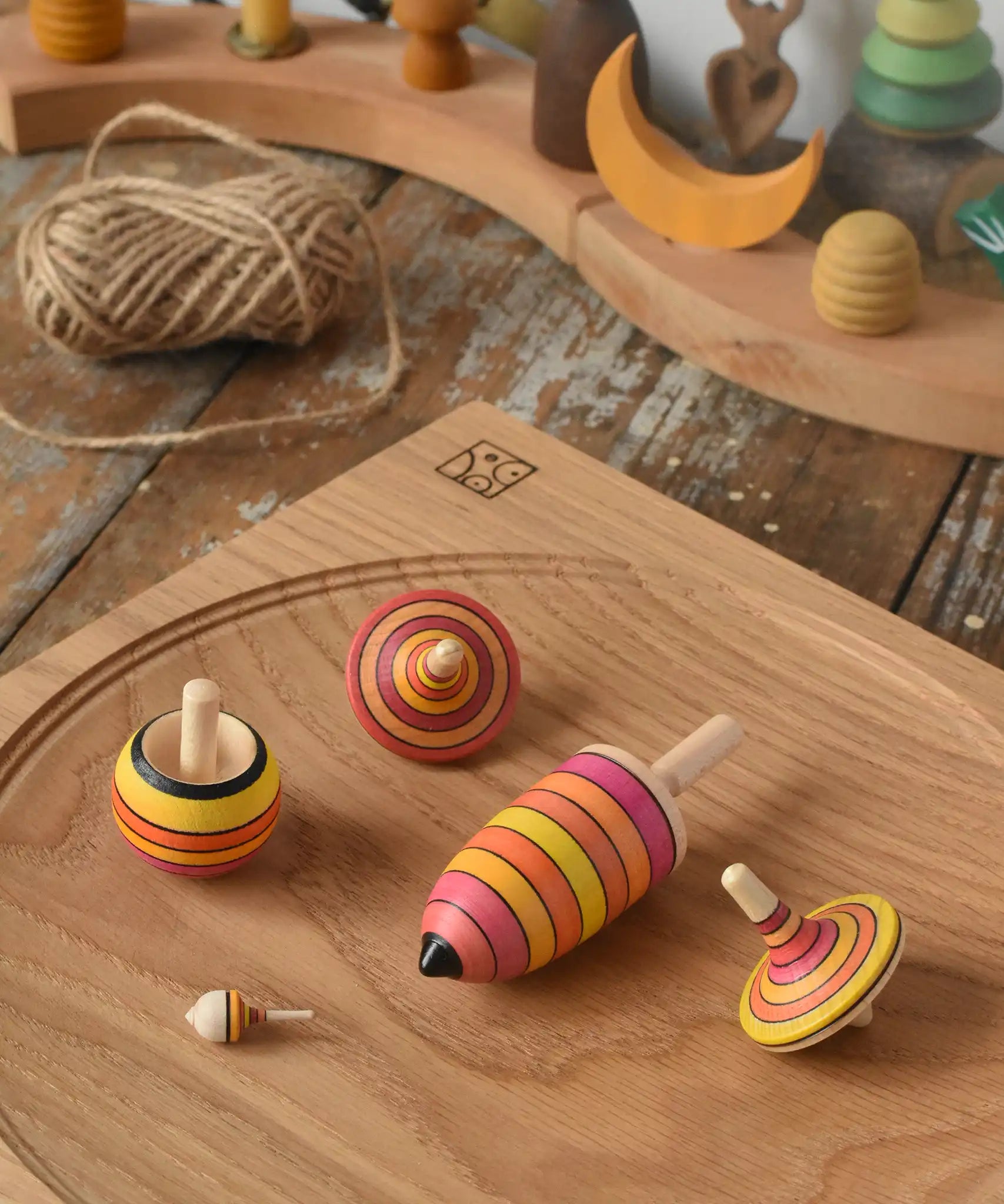Mader fire spinning top learning set placed on an oak spinning plate on a wooden surface in the Babipur playroom.