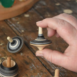 Rallye top from the Mader Kreiselmanufaktur graphite spinning top learning set in an adult's hand in the Babipur playroom. 