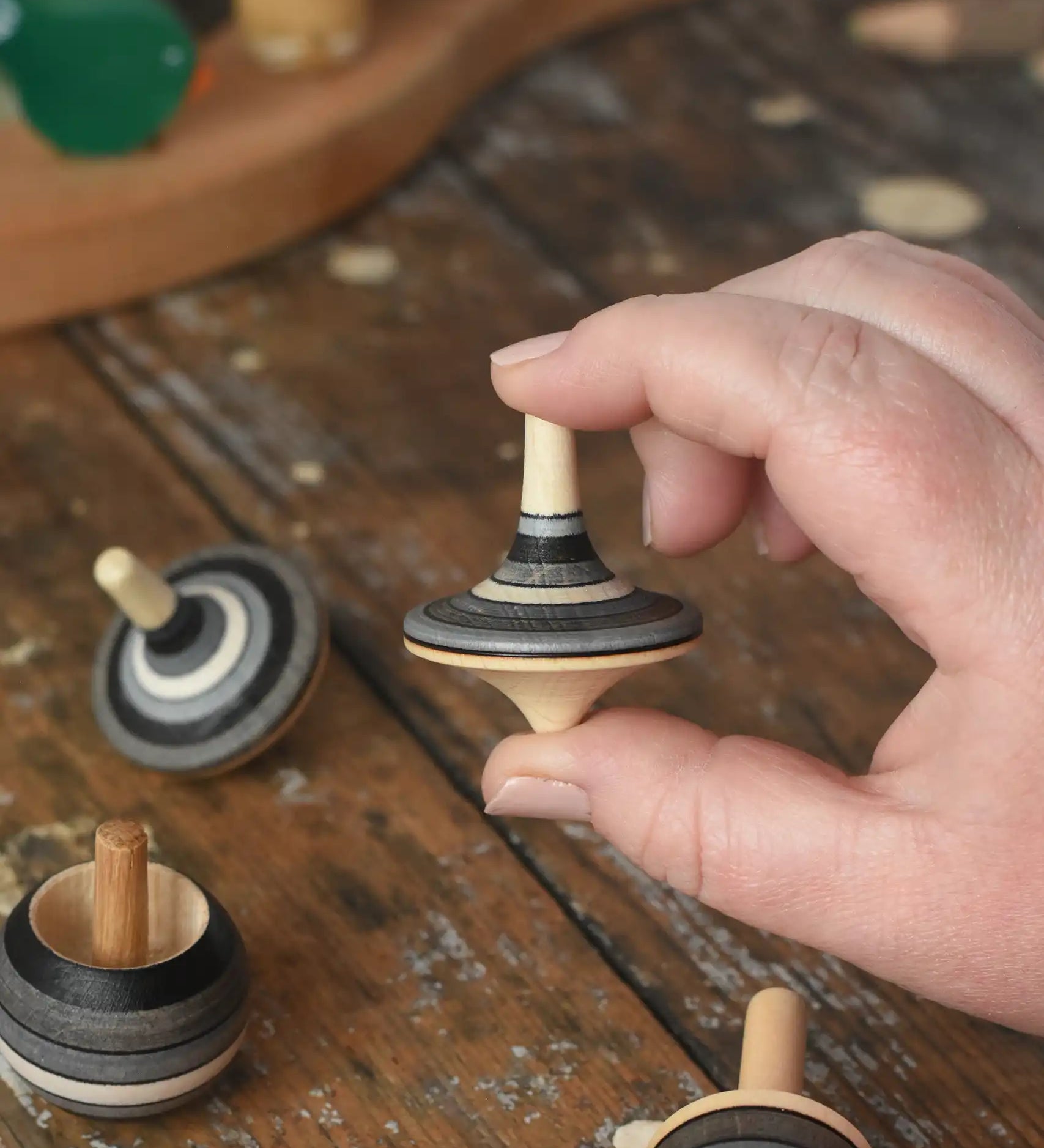 Rallye top from the Mader Kreiselmanufaktur graphite spinning top learning set in an adult's hand in the Babipur playroom. 