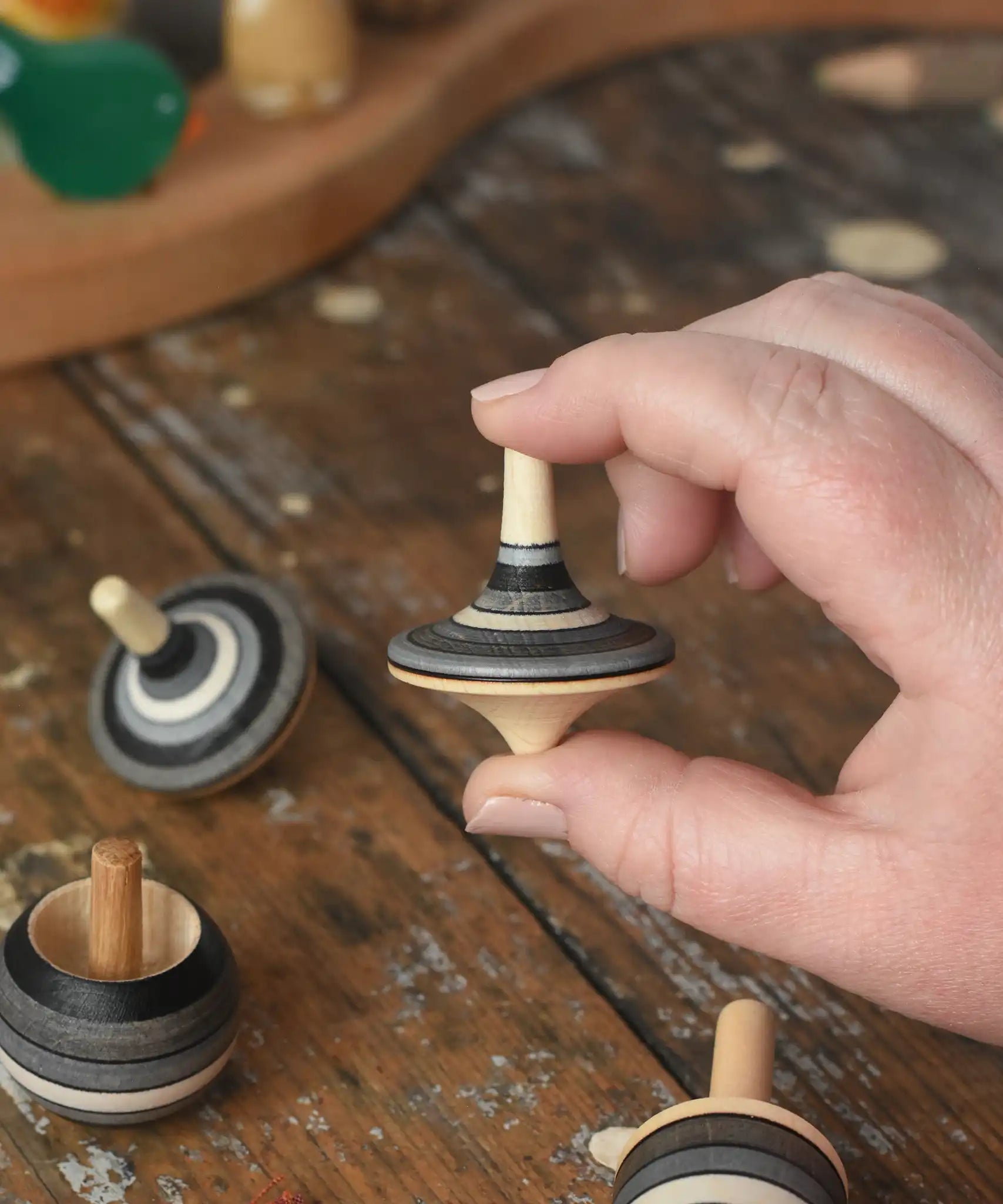 Rallye top from the Mader Kreiselmanufaktur graphite spinning top learning set in an adult's hand in the Babipur playroom. 