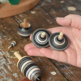 Rallye spinners from the Mader Kreiselmanufaktur graphite spinning top learning set in an adult's hand in the Babipur playroom. 