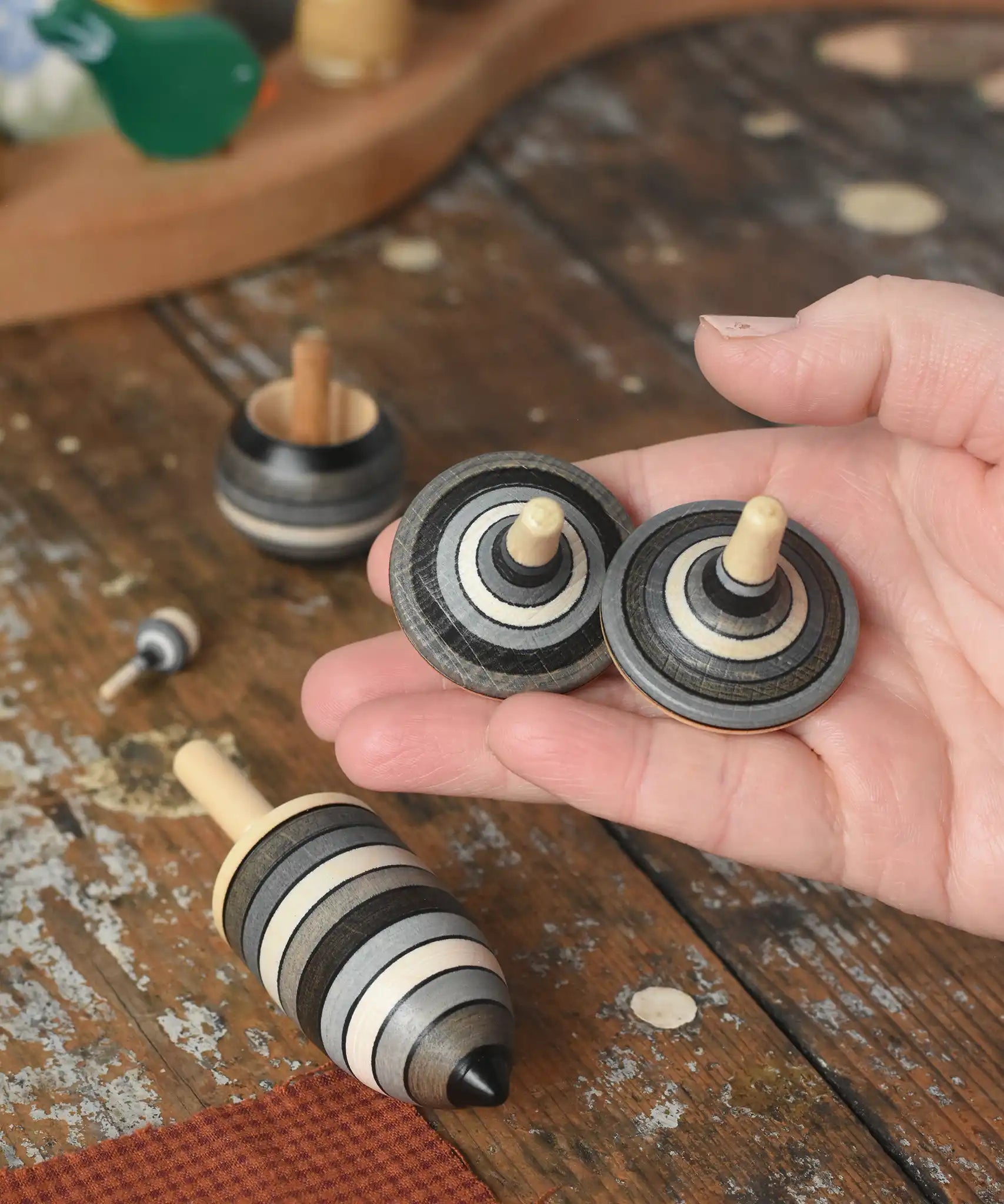 Rallye spinners from the Mader Kreiselmanufaktur graphite spinning top learning set in an adult's hand in the Babipur playroom. 