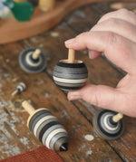 Turover top spinner from the Mader Kreiselmanufaktur graphite spinning top learning set in an adult's hand in the Babipur playroom. 