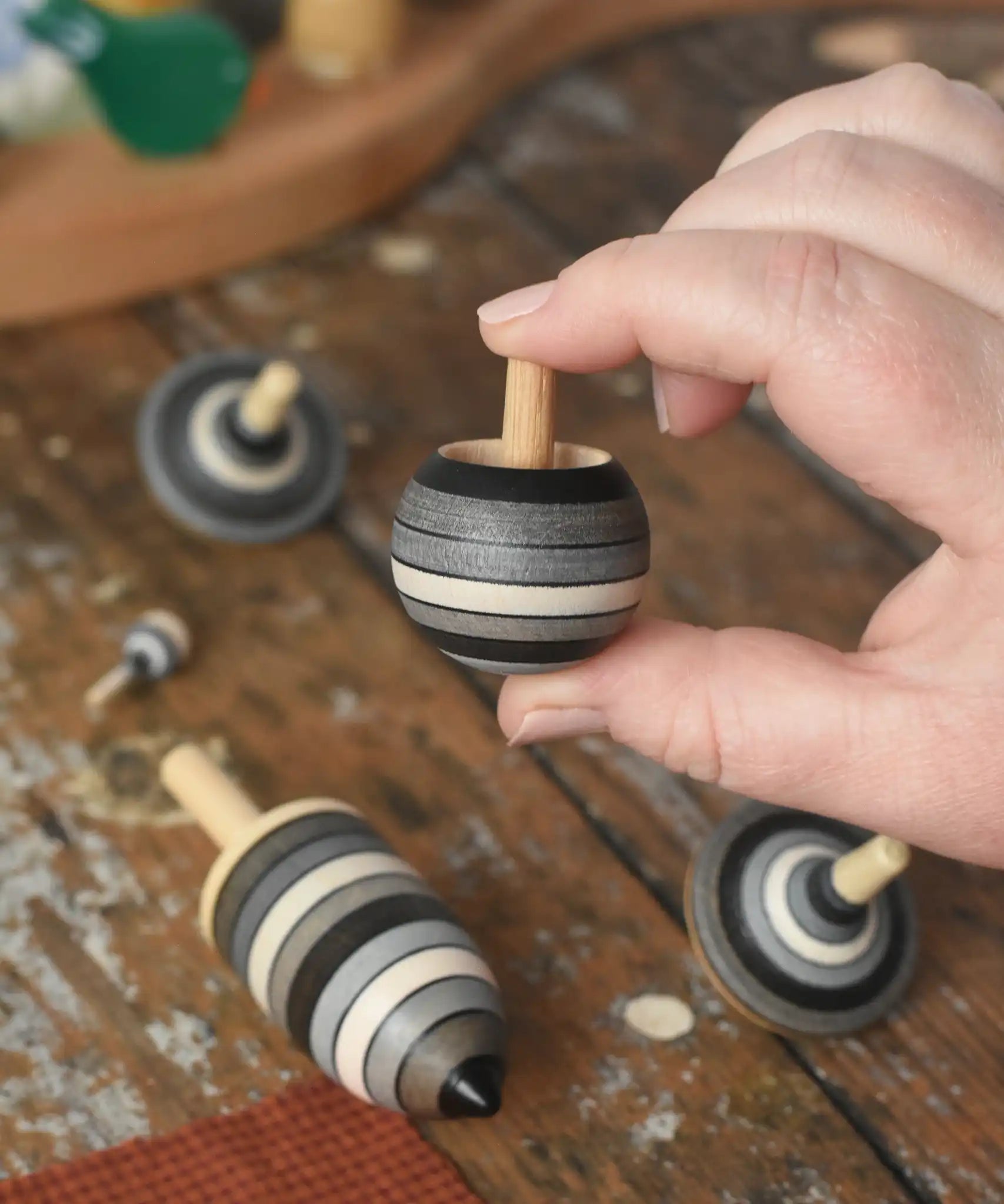 Turover top spinner from the Mader Kreiselmanufaktur graphite spinning top learning set in an adult's hand in the Babipur playroom. 
