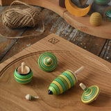 Mader Kreiselmanufaktur green grass spinning top learning set placed on an oak spinning plate wooden surface in the Babipur playroom. 
