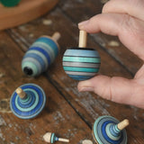 Turnover spinner from the Mader Kreiselmanufaktur ice blue spinning top learning set in an adult's hand in the Babipur playroom. 