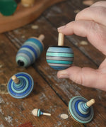 Turnover spinner from the Mader Kreiselmanufaktur ice blue spinning top learning set in an adult's hand in the Babipur playroom. 