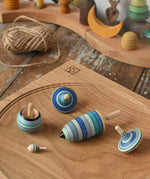 Mader Kreiselmanufaktur ice blue spinning top learning set on an oak spinning plate on a wooden surface in the Babipur playroom. 