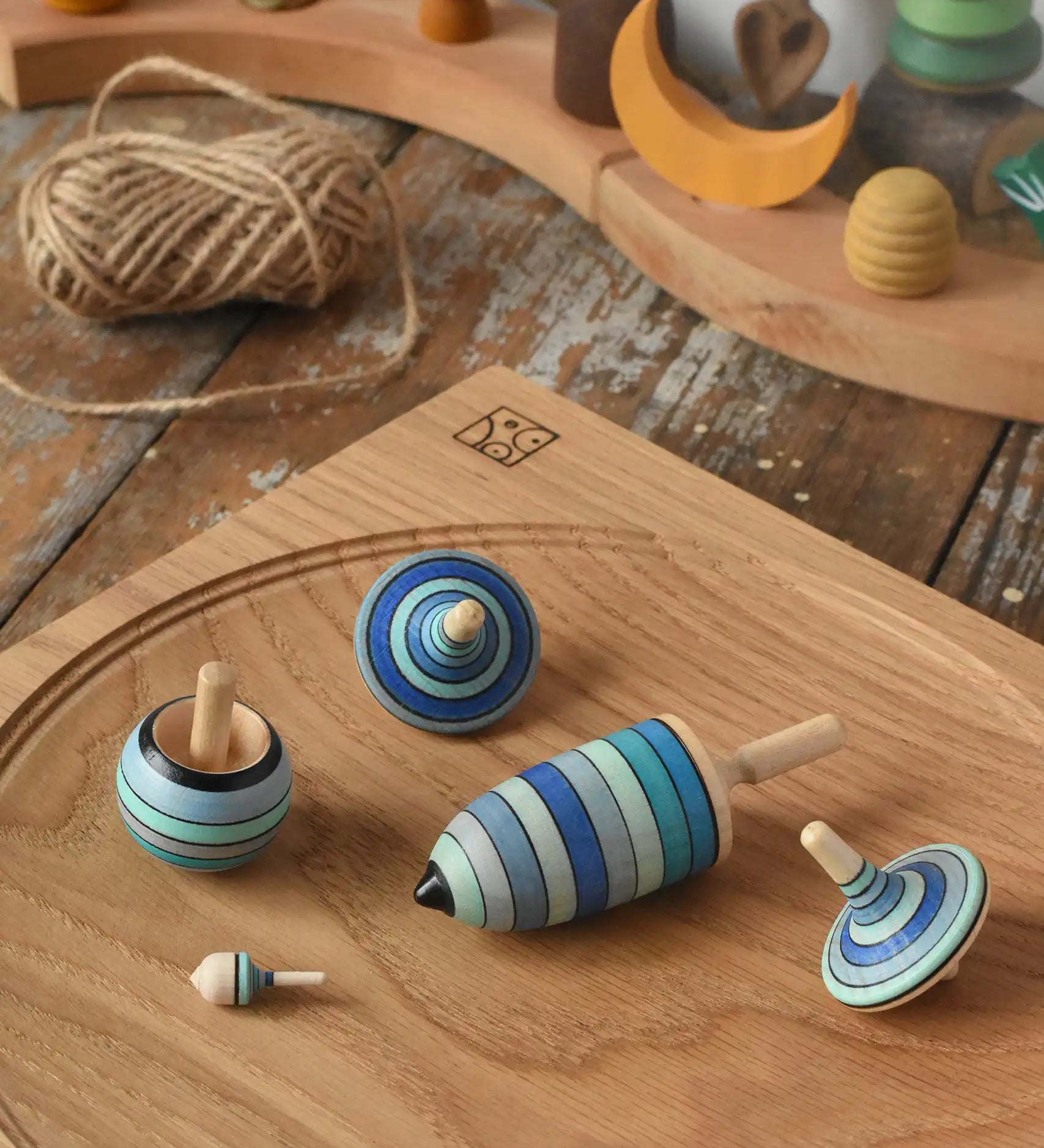Mader Kreiselmanufaktur ice blue spinning top learning set on an oak spinning plate on a wooden surface in the Babipur playroom. 