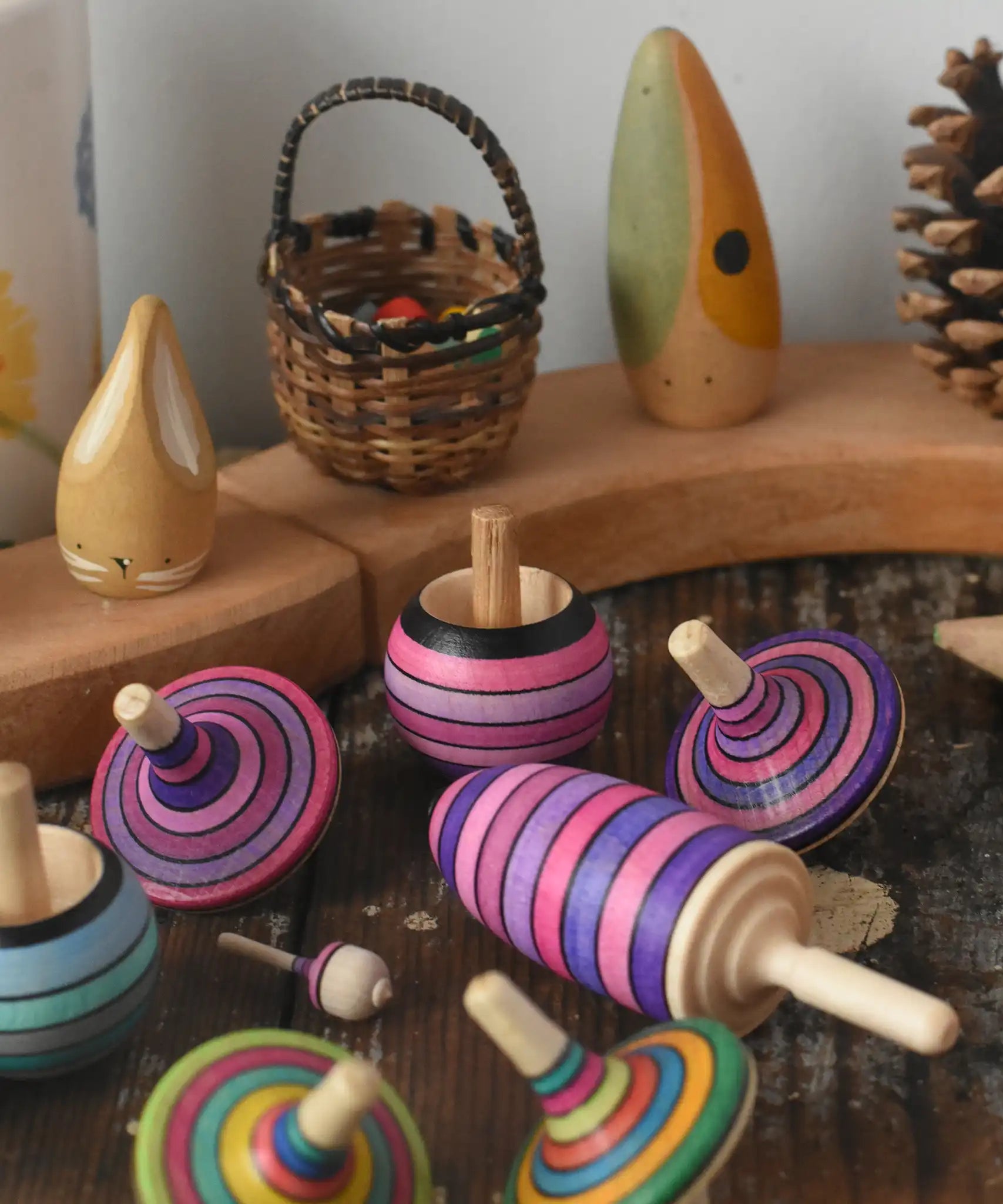 Mader lilac purple spinning top learning set placed on a wooden surface in the Babipur playroom. Grimm's celebration ring set up in the background.