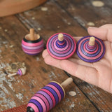 Mader lilac purple spinning top learning set placed on a wooden surface in the Babipur playroom. The two rallye tops are on an adult's hand.