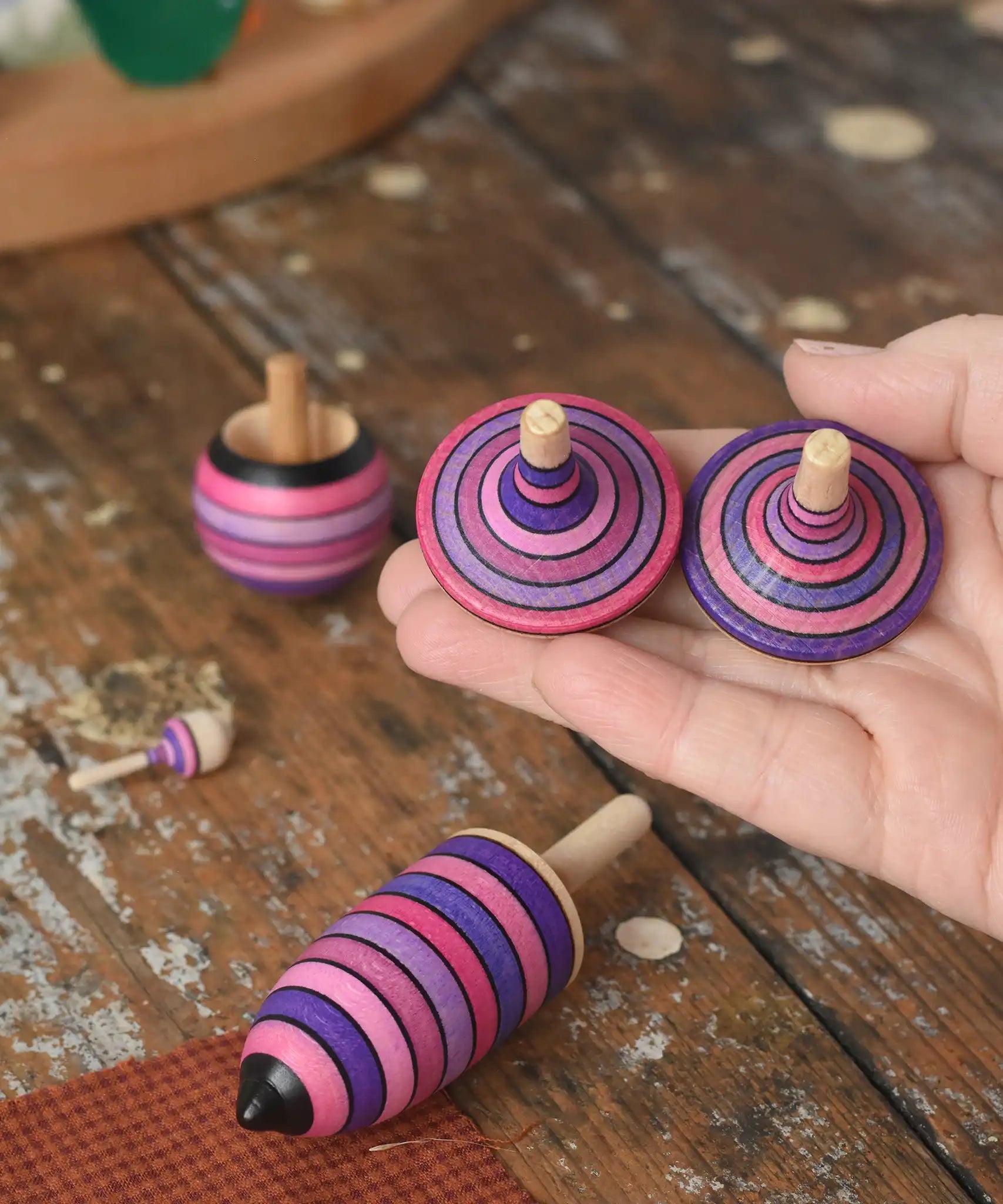 Mader lilac purple spinning top learning set placed on a wooden surface in the Babipur playroom. The two rallye tops are on an adult's hand.