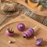 Mader lilac purple spinning top learning set placed on an oak spinning plate on a wooden surface in the Babipur playroom. 