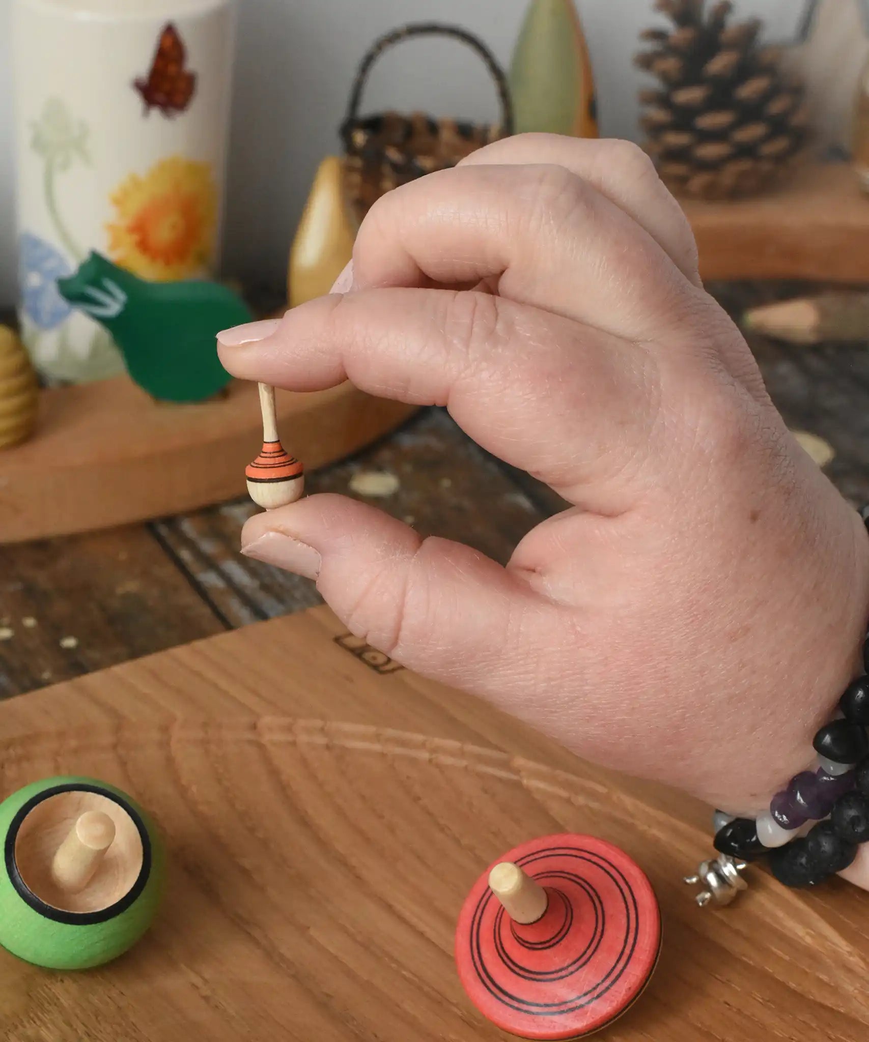 The miniature spinning top from the Mader Kreiselmanufaktur multicolour spinning top learning set in an adult's hand in the Babipur playroom.