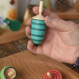 Blue thunderbolt spinning top from the Mader Kreiselmanufaktur multicolour spinning top learning set in an adult's hand in the Babipur playroom. 