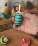 Blue thunderbolt spinning top from the Mader Kreiselmanufaktur multicolour spinning top learning set in an adult's hand in the Babipur playroom. 