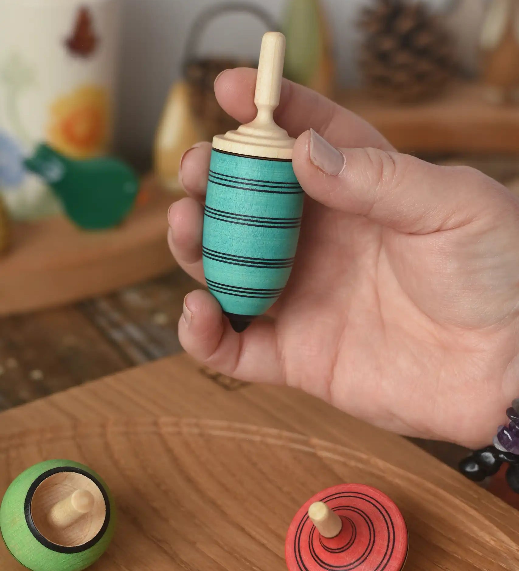 Blue thunderbolt spinning top from the Mader Kreiselmanufaktur multicolour spinning top learning set in an adult's hand in the Babipur playroom. 