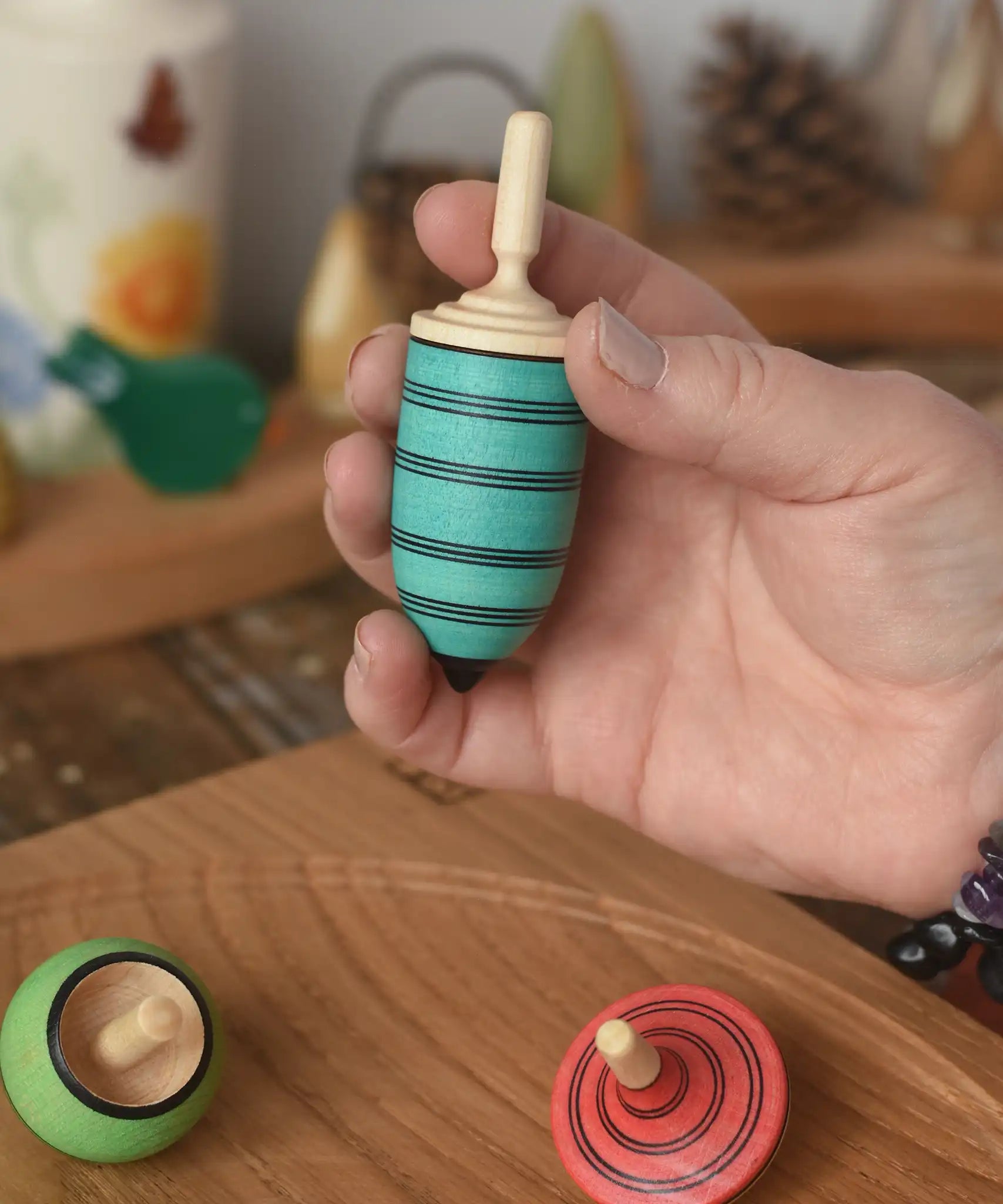 Blue thunderbolt spinning top from the Mader Kreiselmanufaktur multicolour spinning top learning set in an adult's hand in the Babipur playroom. 