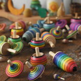 Mader Kreiselmanufaktur rainbow spinning top learning set placed on a wooden surface in the Babipur playroom. Other colour variations of the same set can be seen in the background.