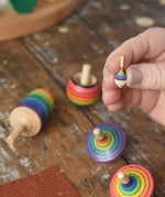 The miniature Mader Kreiselmanufaktur rainbow spinning top from the rainbow spinning top learning set in an adult's hand in the Babipur playroom. 