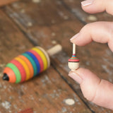 Miniature spinner from the Mader Kreiselmanufaktur striped spinning top learning set in an adult's hand in the Babipur playroom. 