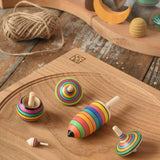 Mader Kreiselmanufaktur striped spinning top learning set placed on an oak spinning plate on a wooden surface in the Babipur playroom. 