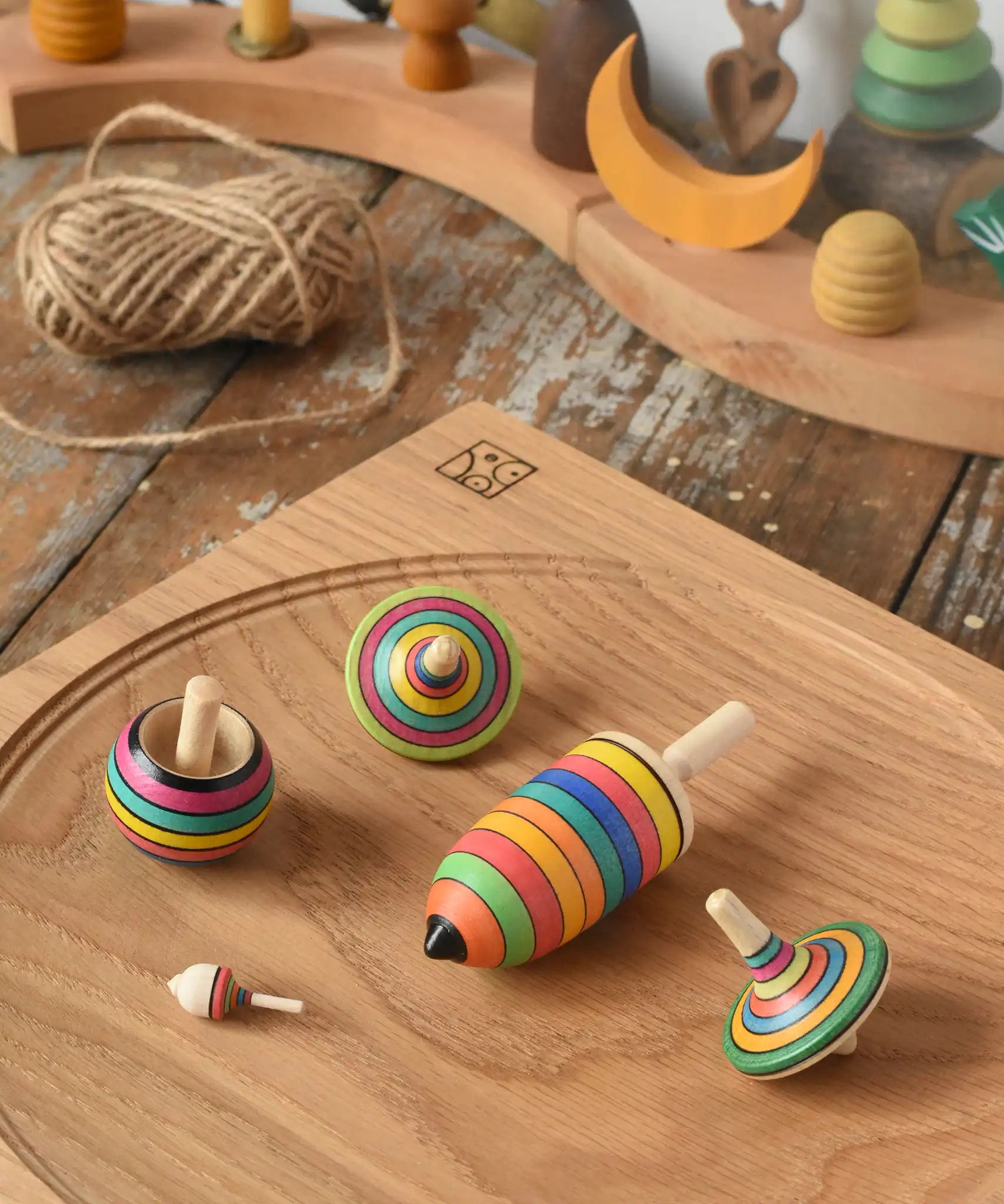 Mader Kreiselmanufaktur striped spinning top learning set placed on an oak spinning plate on a wooden surface in the Babipur playroom. 