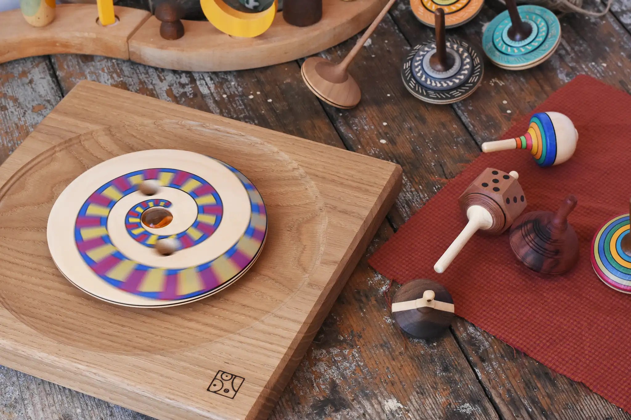 Collection of handmade Mader wooden spinning tops toys placed on a wooden desk in the Babipur playroom.