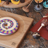 Collection of handmade Mader wooden spinning tops toys placed on a wooden desk in the Babipur playroom.