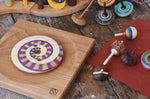 Collection of handmade Mader wooden spinning tops toys placed on a wooden desk in the Babipur playroom.