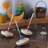 Three Mader Rainbow Spaghetti Spinning Tops in placed on a desk in the Babipur playroom. 