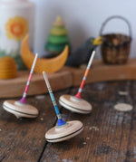 Three Mader Rainbow Spaghetti Spinning Tops in placed on a desk in the Babipur playroom. 
