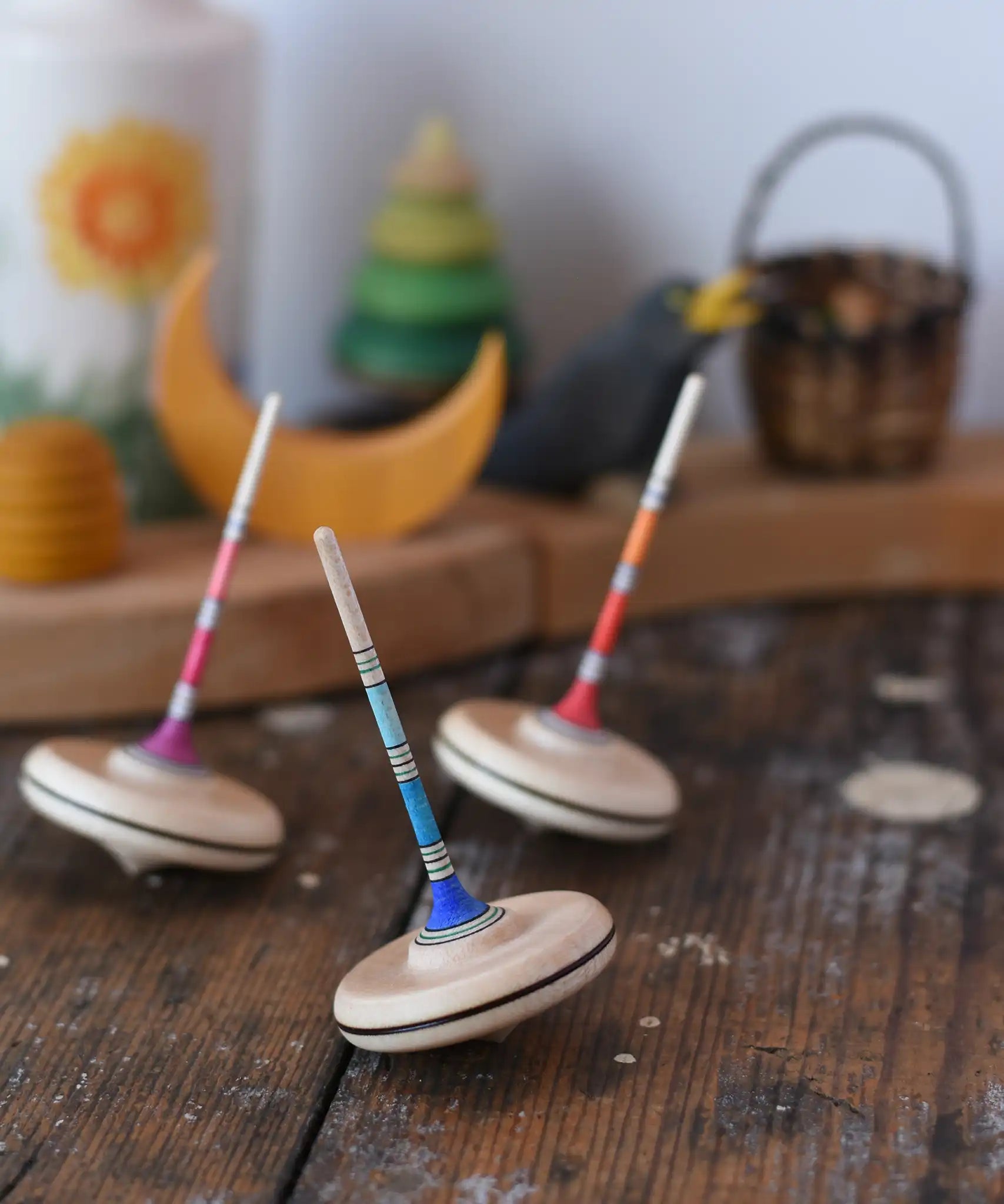 Three Mader Rainbow Spaghetti Spinning Tops in placed on a desk in the Babipur playroom. 