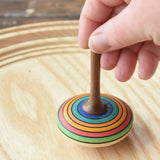 Mader stripe spinning top placed on a spinning plate held upright by an adult hand. 
