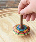 Mader stripe spinning top placed on a spinning plate held upright by an adult hand. 