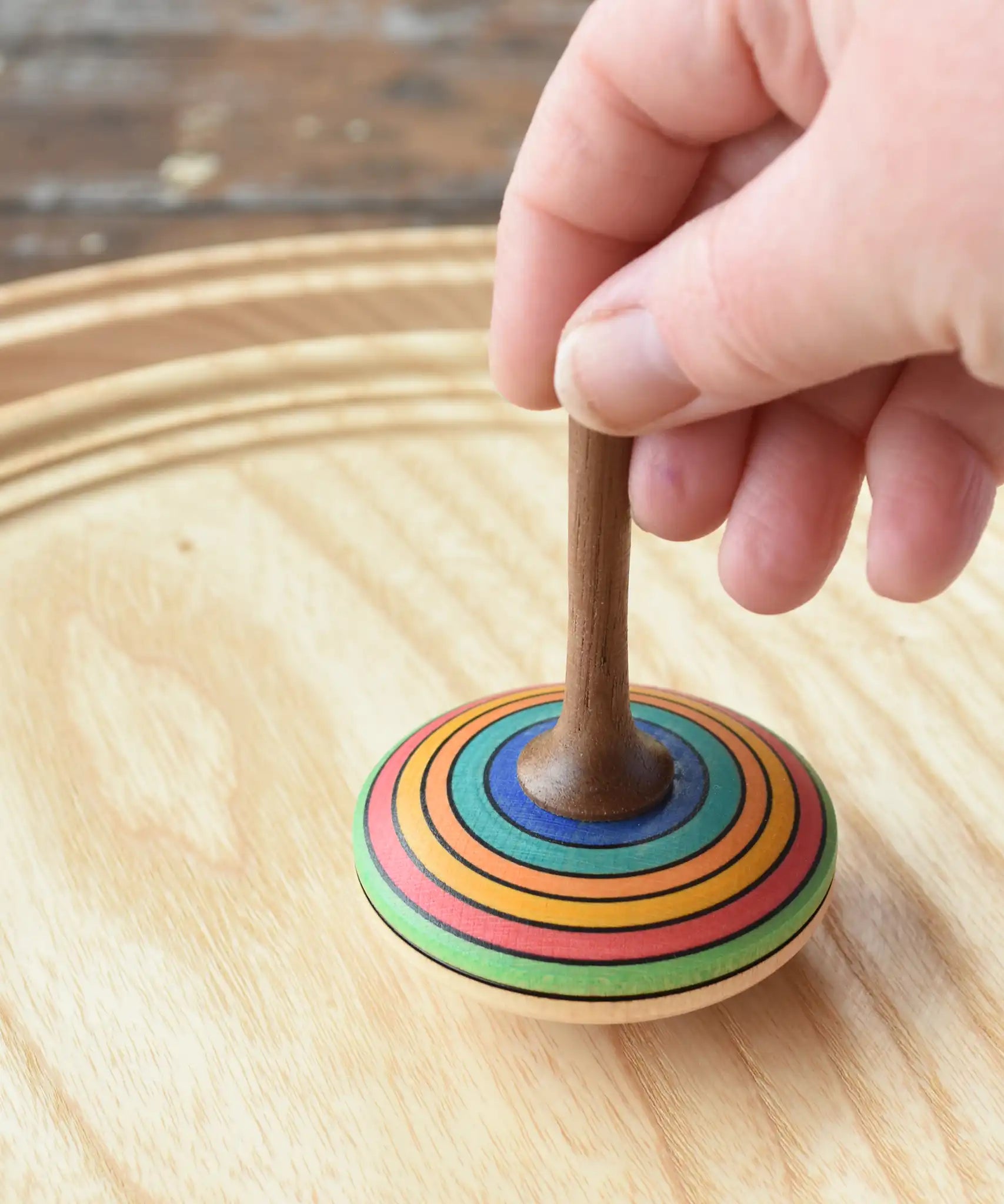 Mader stripe spinning top placed on a spinning plate held upright by an adult hand. 
