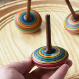 Mader stripe spinning tops placed on a spinning plate with one in an adult's hand. 