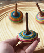 Mader stripe spinning tops placed on a spinning plate with one in an adult's hand. 