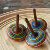 Three Mader stripe spinning tops placed on a spinning plate. 