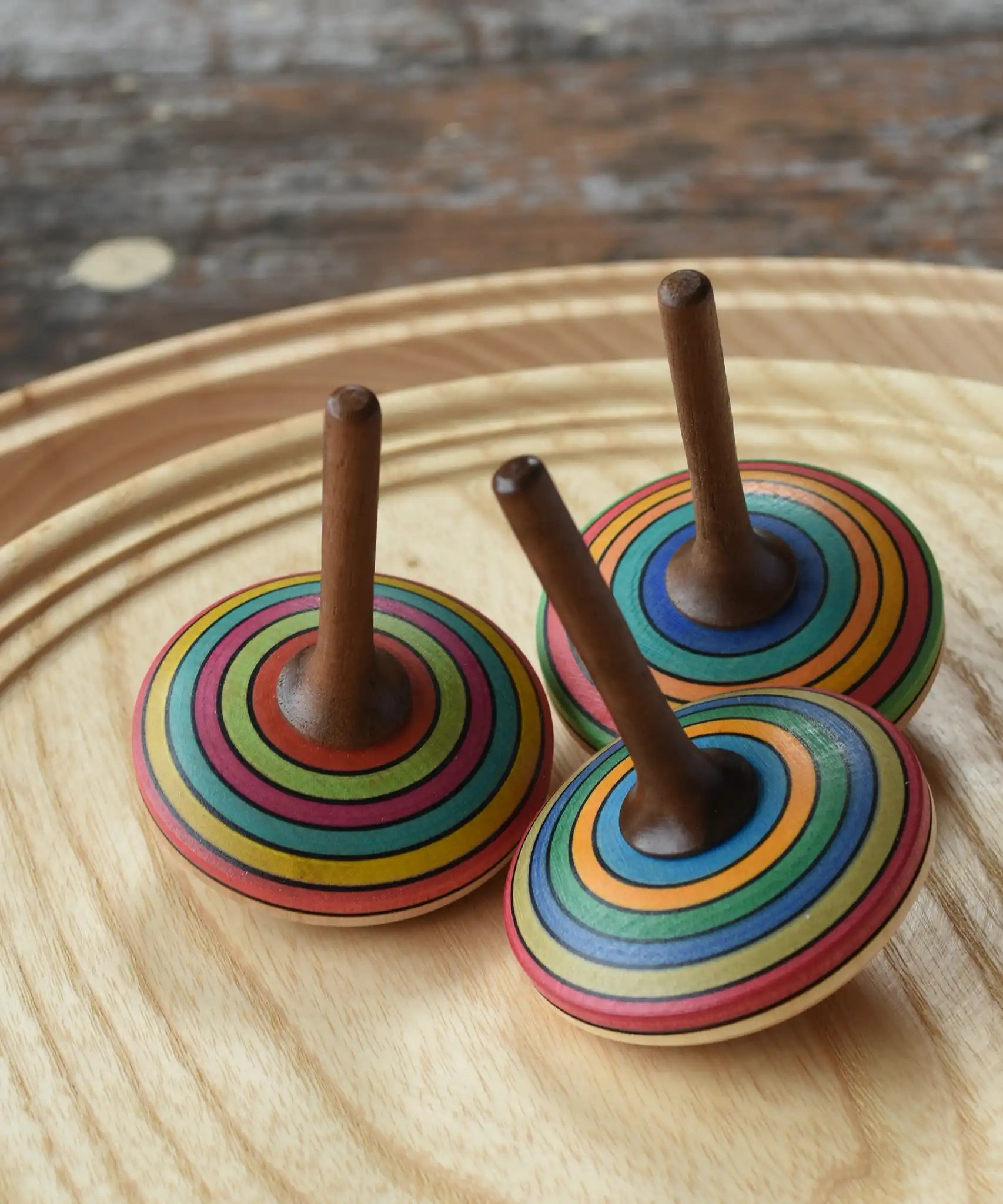 Three Mader stripe spinning tops placed on a spinning plate. 