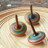 Three Mader stripe spinning tops placed on a spinning plate. 