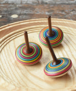 Three Mader stripe spinning tops placed on a spinning plate. 