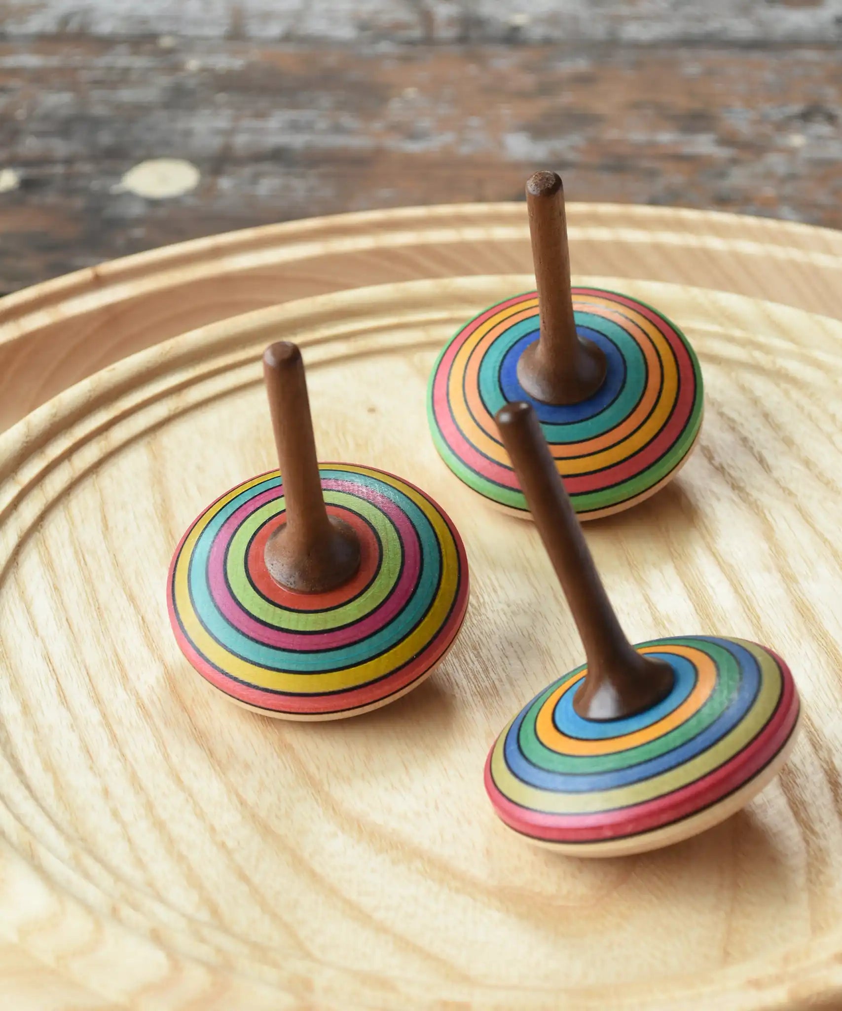 Three Mader stripe spinning tops placed on a spinning plate. 