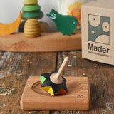 Mader Kreiselmanufaktur superstar wooden spinning top toy with and spinning plate placed on a wooden desk in the Babipur playroom.