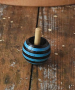 Blue striped Mader tango turn-over spinning top placed on a wooden desk in the Babipur playroom. 