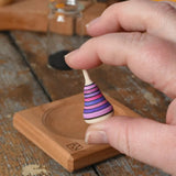 Mader Tarantella On Stage mini spinning top in an adult hand in the Babipur playroom. 