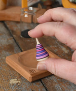 Mader Tarantella On Stage mini spinning top in an adult hand in the Babipur playroom. 