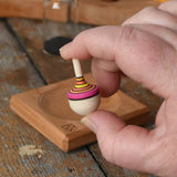 Mader Tarantella On Stage mini spinning top in an adult hand in the Babipur playroom. 